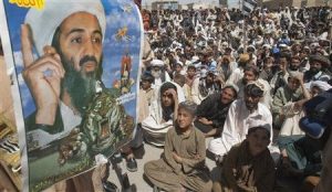 Al Qaeda supporters seated by a picture of Osama bin Laden.